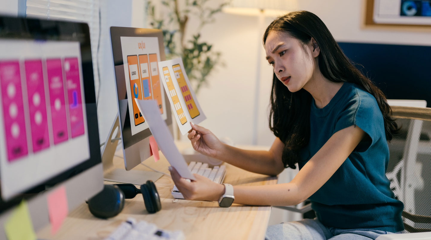 Vue plongeante sur un bureau avec une carte de visite, un smartphone affichant un site web et une plaquette papier éparpillés