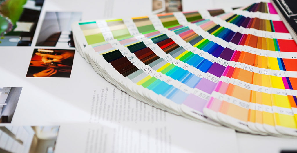 Une main tient une charte graphique imprimée avec un nuancier de couleurs dans un environnement de travail créatif